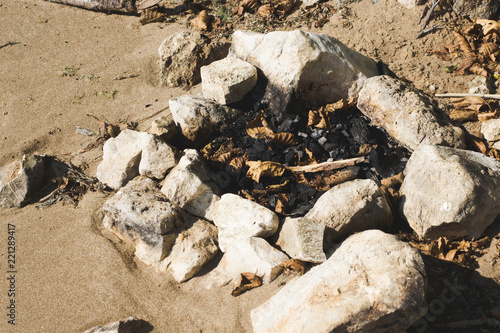 campfire strewn with stones and leaves in a beach