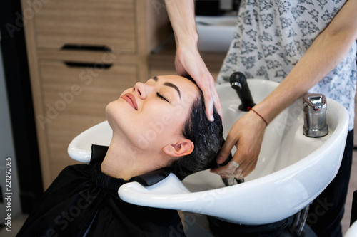 beauty and people concept - happy young woman with hairdresser washing head at hair salon