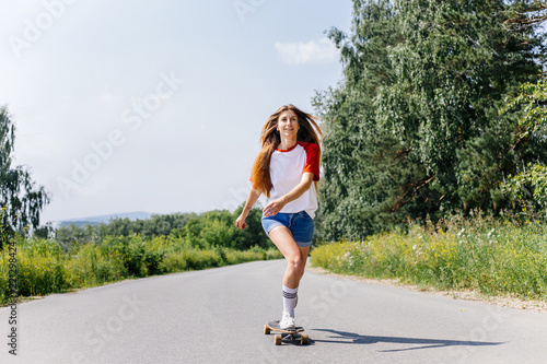 Beautiful skater woman riding on her longboard in the city © Nichizhenova Elena