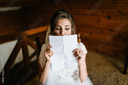 Φωτογραφία Beautiful bride reading, kissing letter from the groom for love