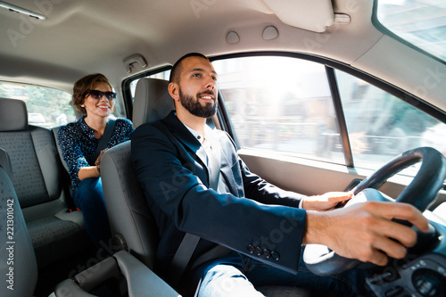 Taxi driver driving a car with businesswoman