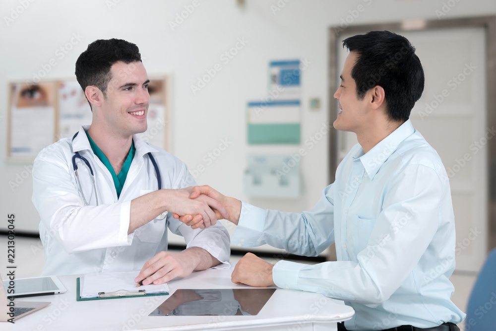 Young doctor shaking the hand of middle-aged patient male Young doctor shaking the hand of middle-aged patient male