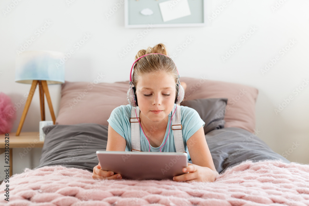 Cute girl using digital tablet in her bedroom Cute girl using digital tablet in her bedroom