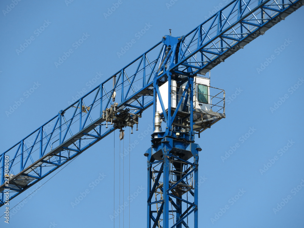 Cabin of construction crane close-up. Building crane isolated on cloudy blue sky background Cabin of construction crane close-up. Building crane isolated on cloudy blue sky background