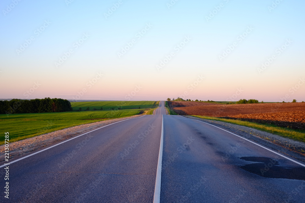 Naklejka premium Wheat field and meadow landscape with road in the sunset time.