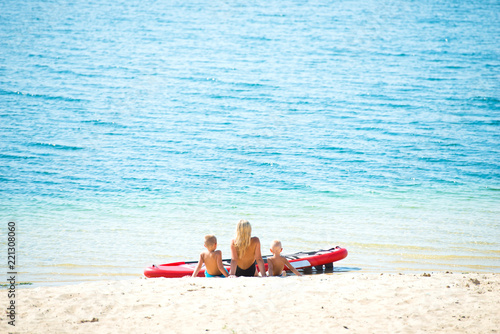 Family sits on the beach and rests after skiing on paddle board .Water sports   active lifestyle.