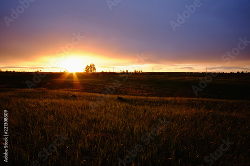Landscape scene and sunset above a field.