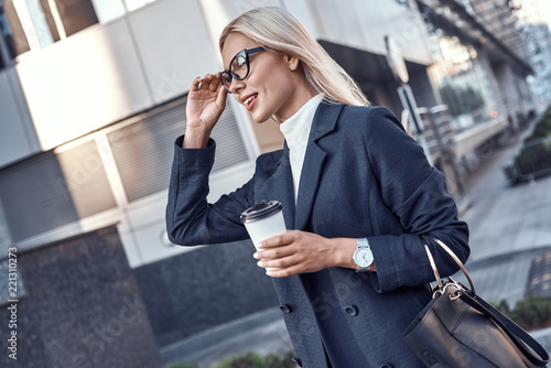 Quadro em tela Cheerful female manager getting to work by foot drinking morning coffee to go wh