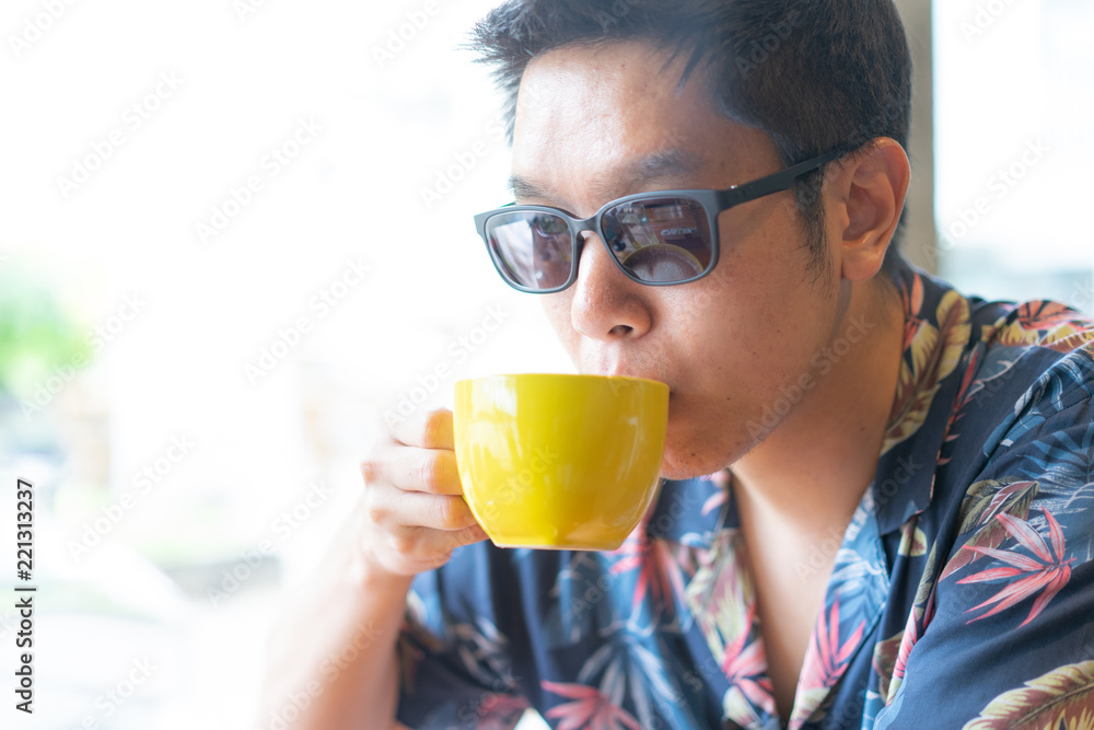 A hipster boy with sunglasses is drinking hot coffee. A hipster boy with sunglasses is drinking hot coffee.