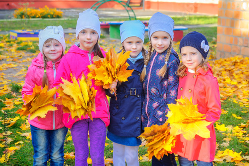 happy girlfriends with large bouquets of autumn leaves