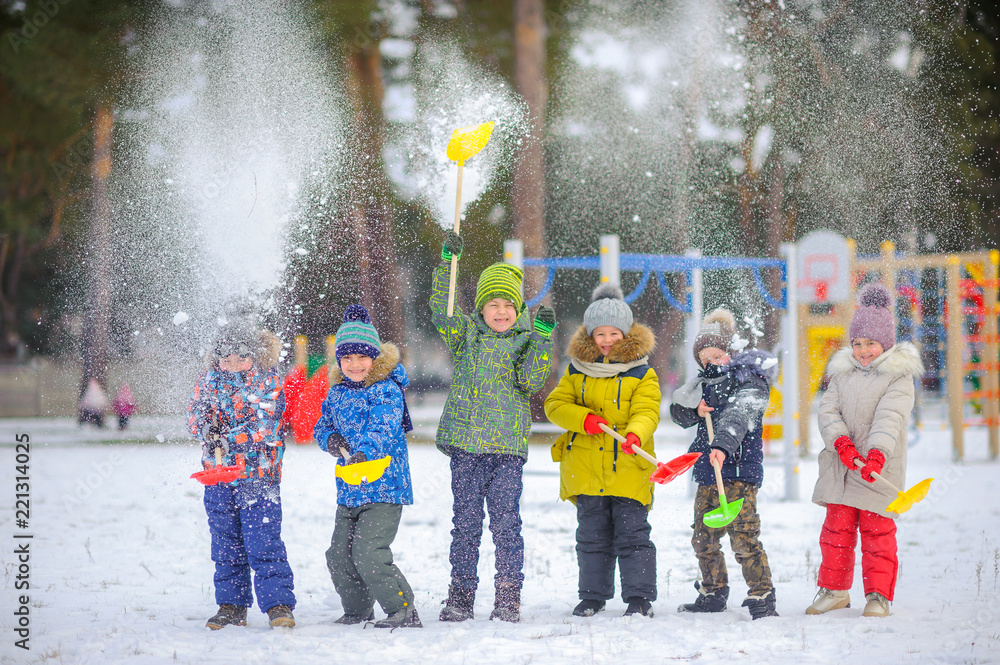 cheerful children play in a winter park, throw snow and have fun