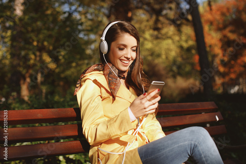 Young woman enjoys music through the headphones in the park