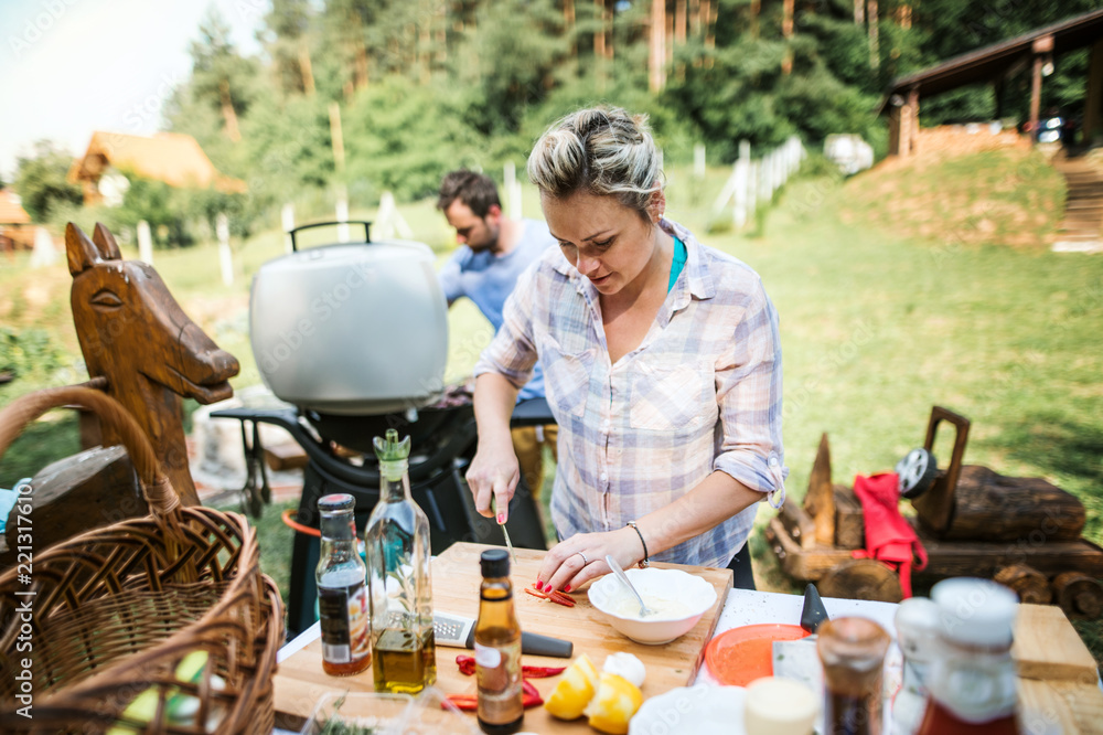 A couple preparing food on a barbecue grill in the backyard. A couple preparing food on a barbecue grill in the backyard.
