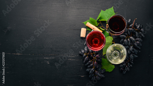 red and white wine in the glasses. Grape. On a black wooden background. Free space for text. Top view.