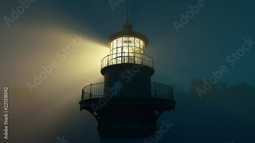 Lighthouse light spinning around. Tall tower standing on the coastline.
