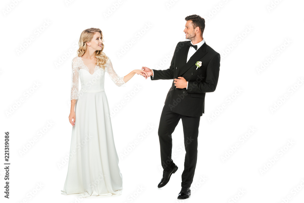 smiling young bride and groom holding hands and looking at each other isolated on white smiling young bride and groom holding hands and looking at each other isolated on white
