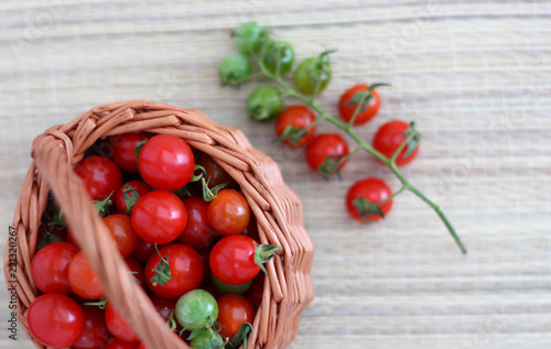small cherry tomatoes lie in a basket and on a bamboo napkin