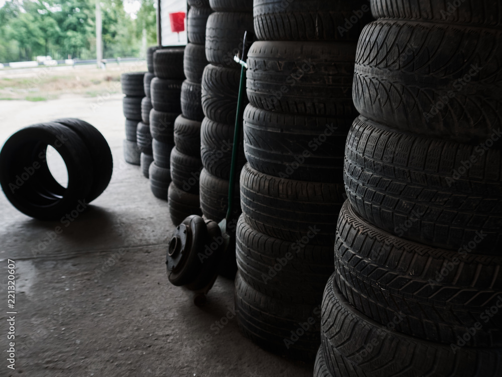 Obraz premium Used car tires stacked in piles at junkyard. Old wheels recycling and utilization concepr