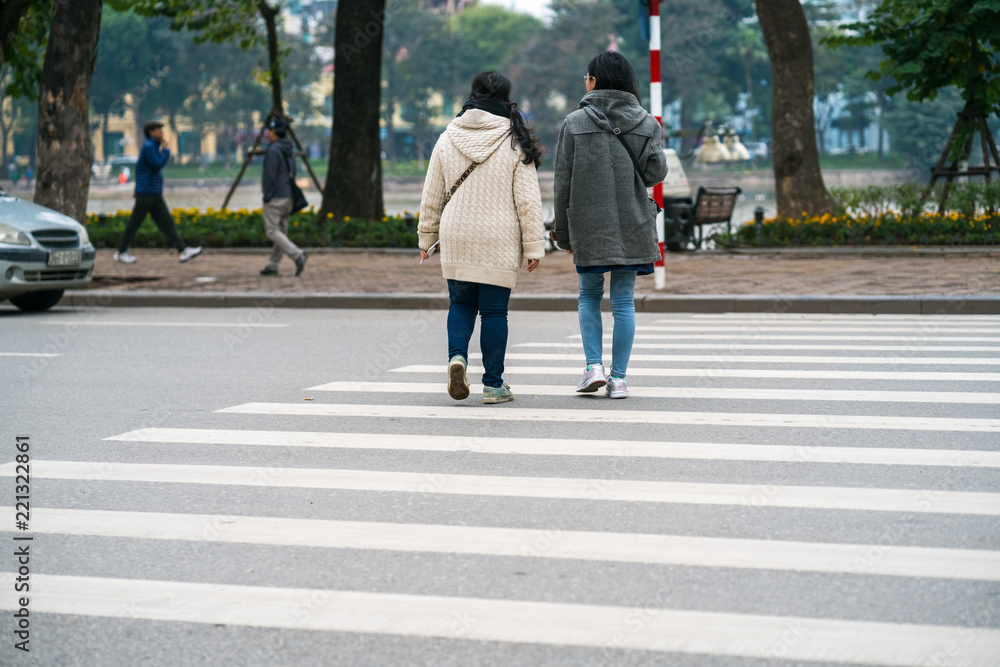 People walking across a street in Hanoi, Vietnam. Closeup People walking across a street in Hanoi, Vietnam. Closeup