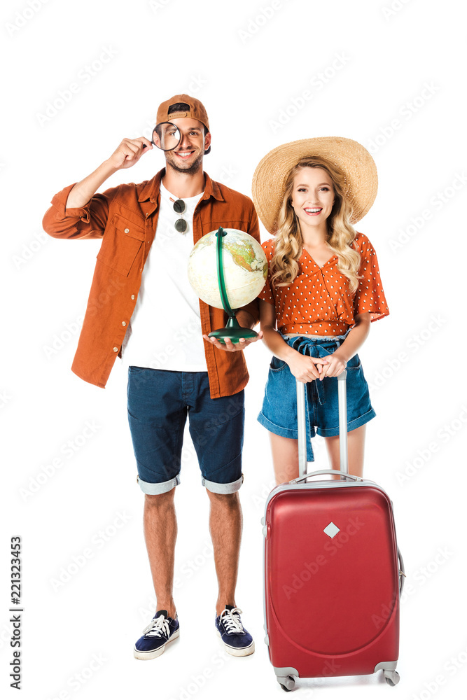 smiling couple standing with magnifying glass, globe and travel bag isolated on white smiling couple standing with magnifying glass, globe and travel bag isolated on white