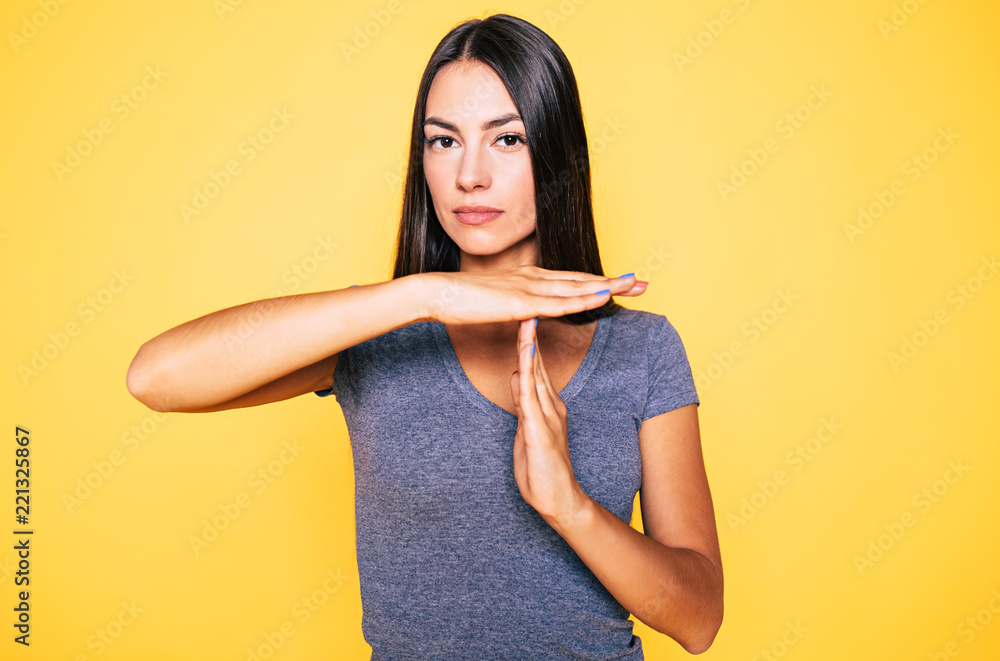 Obraz premium Stop and think. Portrait of young confident beautiful woman in casual wear is doing T symbol or sign with help of her hands and looks on camera