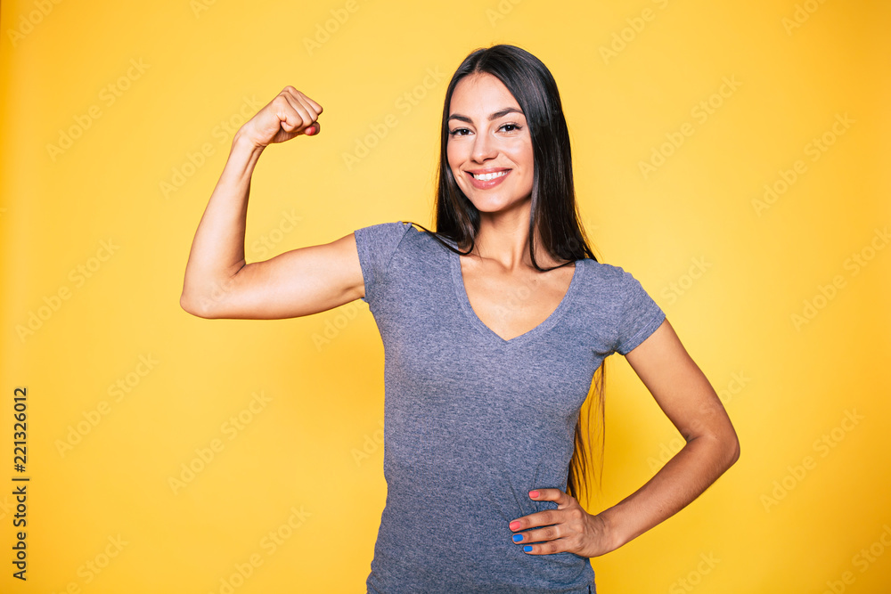 Sport, healthy lifestyle, gym, good body condition, women health, fitness  concepts. Close up Portrait of Young cute sporty smiling brunette woman  while she shows her arms and biceps on camera Stock Photo