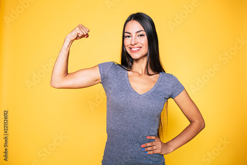 Sport, healthy lifestyle, gym, good body condition, women health, fitness concepts. Close up Portrait of Young cute sporty smiling brunette woman while she shows her arms and biceps on camera