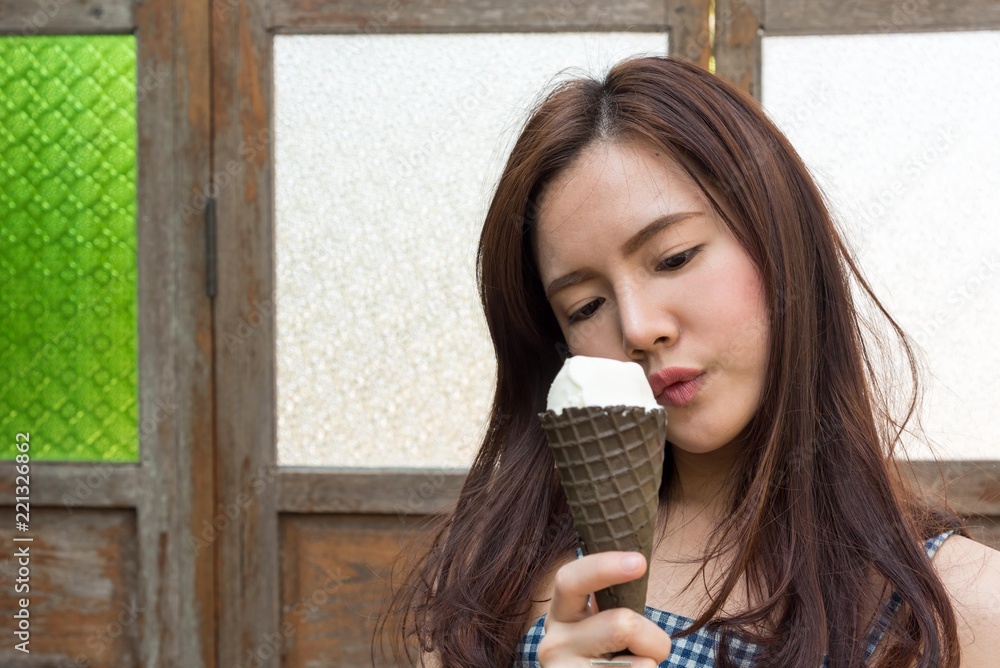 Outdoor closeup fashion portrait of young hipster crazy eating ice cream in hot weather have fun and good mood. asian women eating a delicious ice cream in summer good mood looking and smiling.