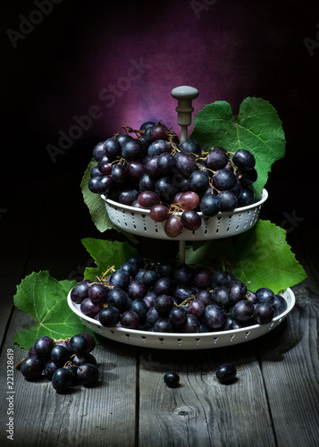 natura morta artistico con uva nera in una fruttiera