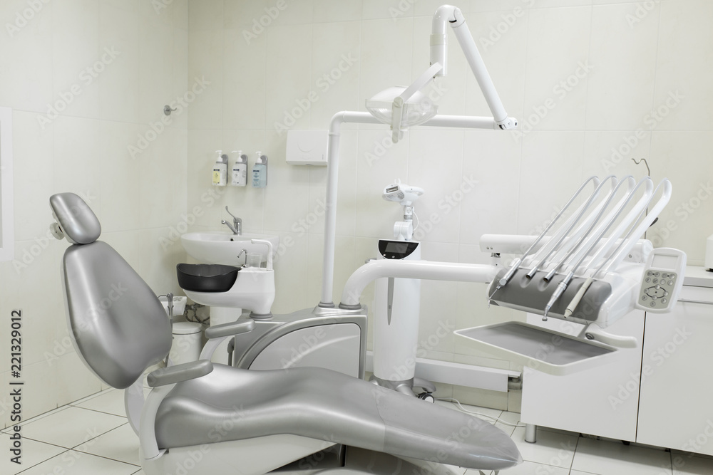 A modern, well-equipped dentist's office, a patient's gray chair. Machine for drilling teeth and other dental equipment A modern, well-equipped dentist's office, a patient's gray chair. Machine for drilling teeth and other dental equipment
