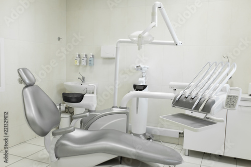 A modern, well-equipped dentist's office, a patient's gray chair. Machine for drilling teeth and other dental equipment