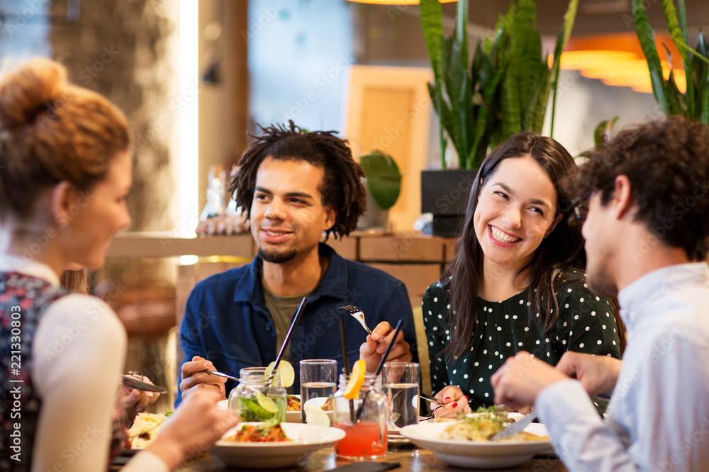 leisure and people concept - happy friends eating at restaurant leisure and people concept - happy friends eating at restaurant