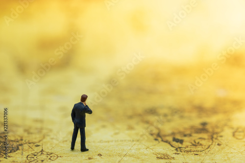 Global Business and Planning concept. Close up of businessman miniature figure standing on center of circle with arrow head on world map.