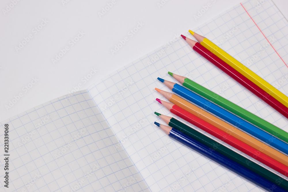 Multicolored pencils on a white notebook Multicolored pencils on a white notebook