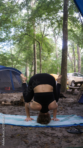 Begginer handstand yoga pose Young woman doing yoga while camping in the forest photo