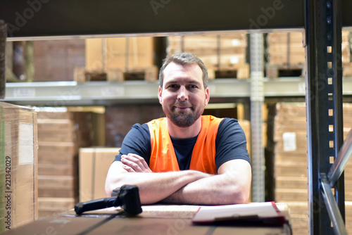 Portrait lächelnder Lagerist im Warenlager einer Spedition im Transportwesen // smiling worker in the warehouse of a freight forwarder