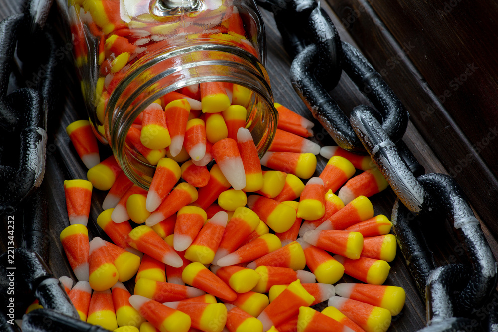 Halloween theme featuring a spilling of candy corn from a jar not a wooden table.