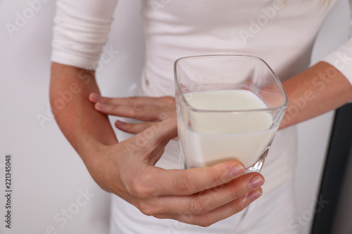 Woman suffering from lactose intolerance holding a galss of milk. Food allergy symptoms rush, itching, skin redness.