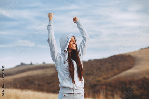 Foto Young sport woman with raised arms motivates herself in nature
