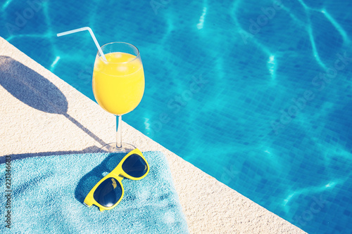 Fotografia Attributes of summer vacation - sunglasses and a glass of juice - on the backgro