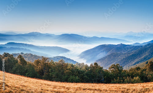 Gorgeous morning scene in high mountains. Fog soar over mountain villages. Panoramic aspect ration. Hiking or any outdoors activity background. Suitable for wallpapers on screen of digital device. 