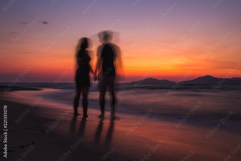 Blurry couple on the beach watching sunset
