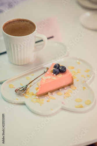 Dessert: pink cheesecake on a white cloud dish, next to a mug of hot chocolate