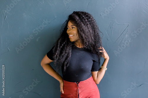 Young African American girl in black tshirt and red trousers. Amazing hairstyle female long curly shine hair. photo