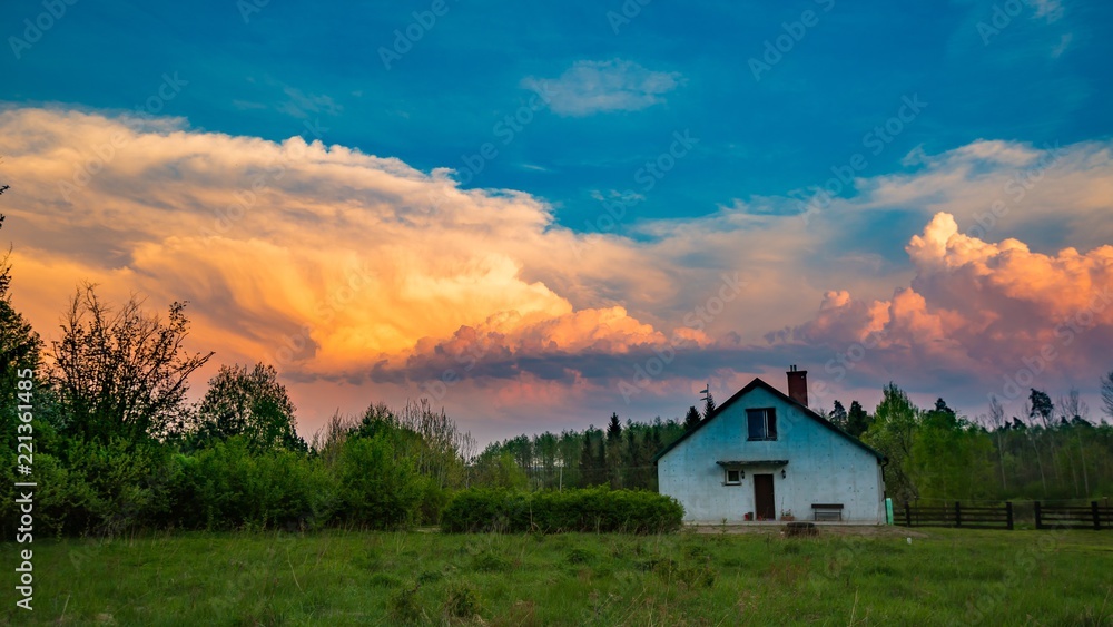 House under stormy sky at sunset