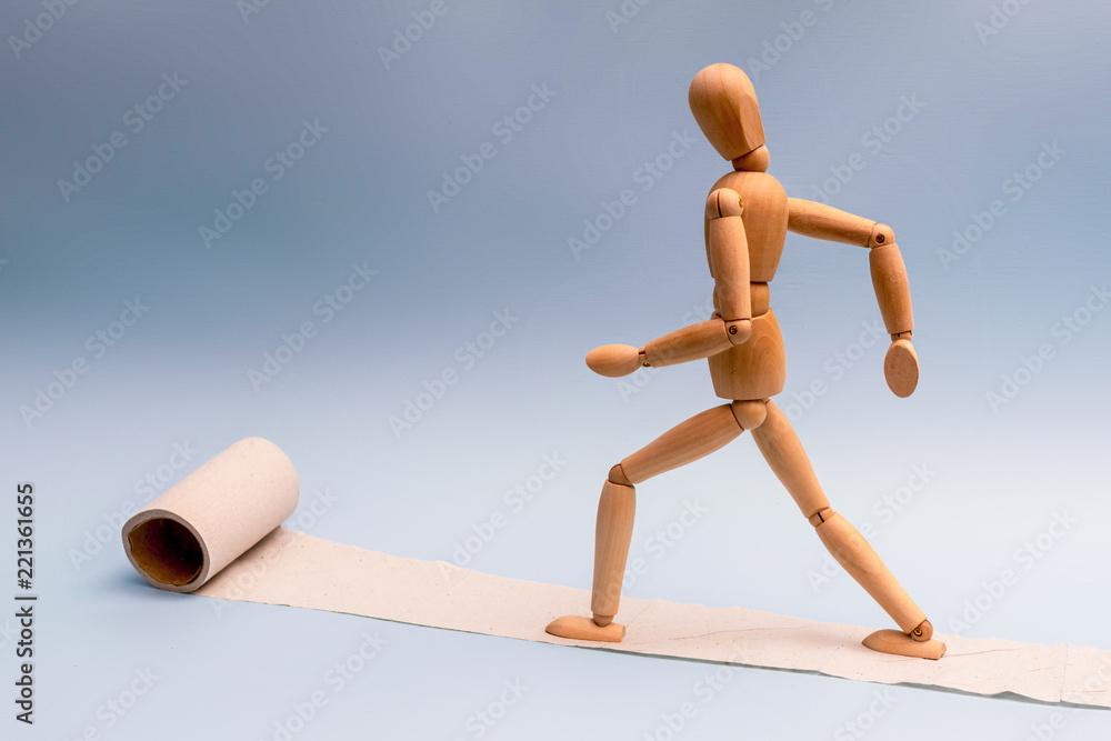 A wooden man is walking on toilet paper A wooden man is walking on toilet paper