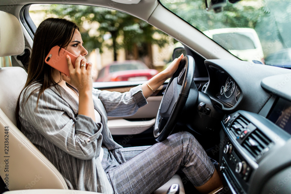 Young business Woman using her phone while driving the car