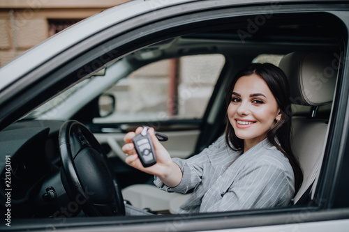 Young happy woman near the car with keys in hand. Concept of buying car