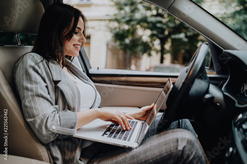 Businesswoman with a laptop in her car in the street