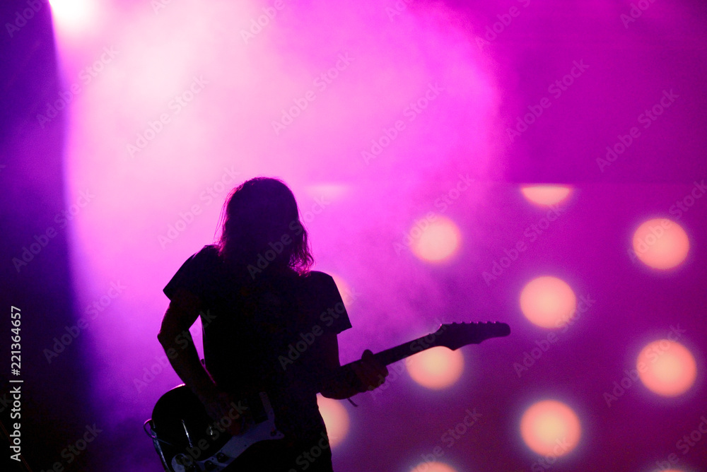 Silhouette of an unregnizable guitarist in a pink background